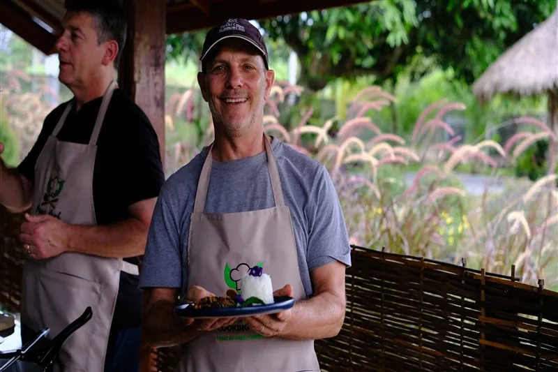 Guest smiling with a Thai dish made during the class