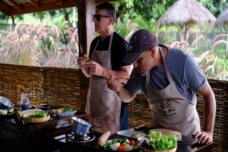 Student seasoning a freshly cooked Thai dish