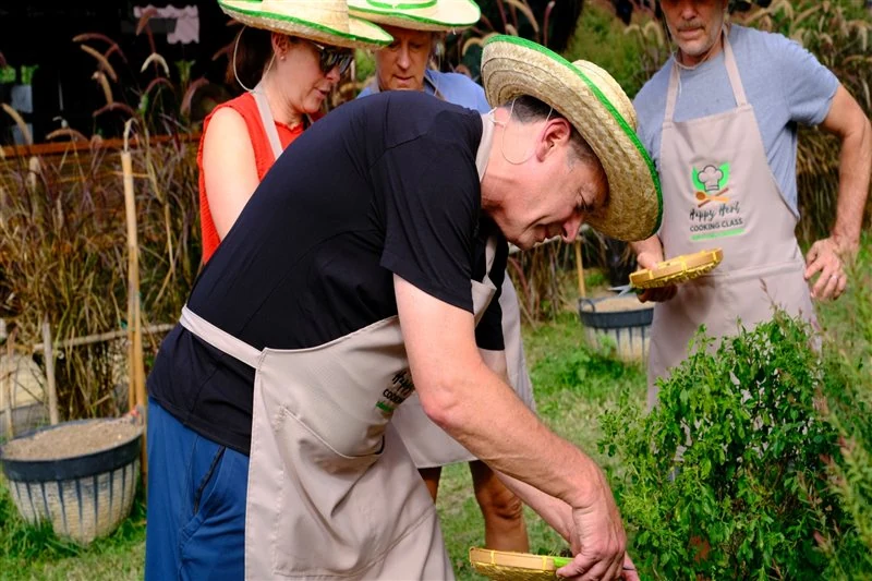 Guests harvesting fresh herbs together before the cooking lesson