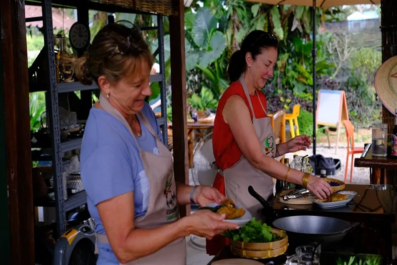 Guest learning a Thai cooking technique from the instructor