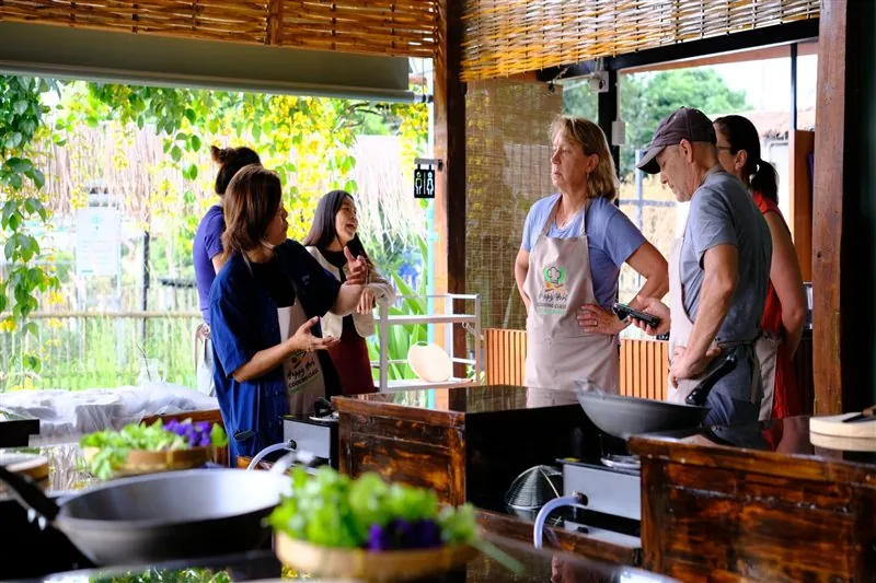 Guest stirring a Thai dish in the garden kitchen