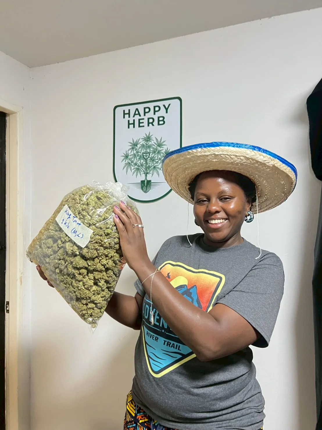 Happy Herb guest smiling while holding a bag of harvested cannabis flowers