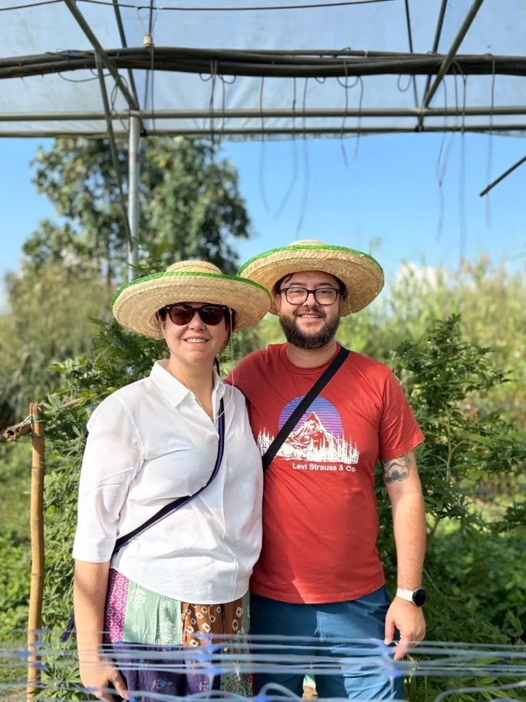 Traveller and local guide smiling inside the cannabis greenhouse