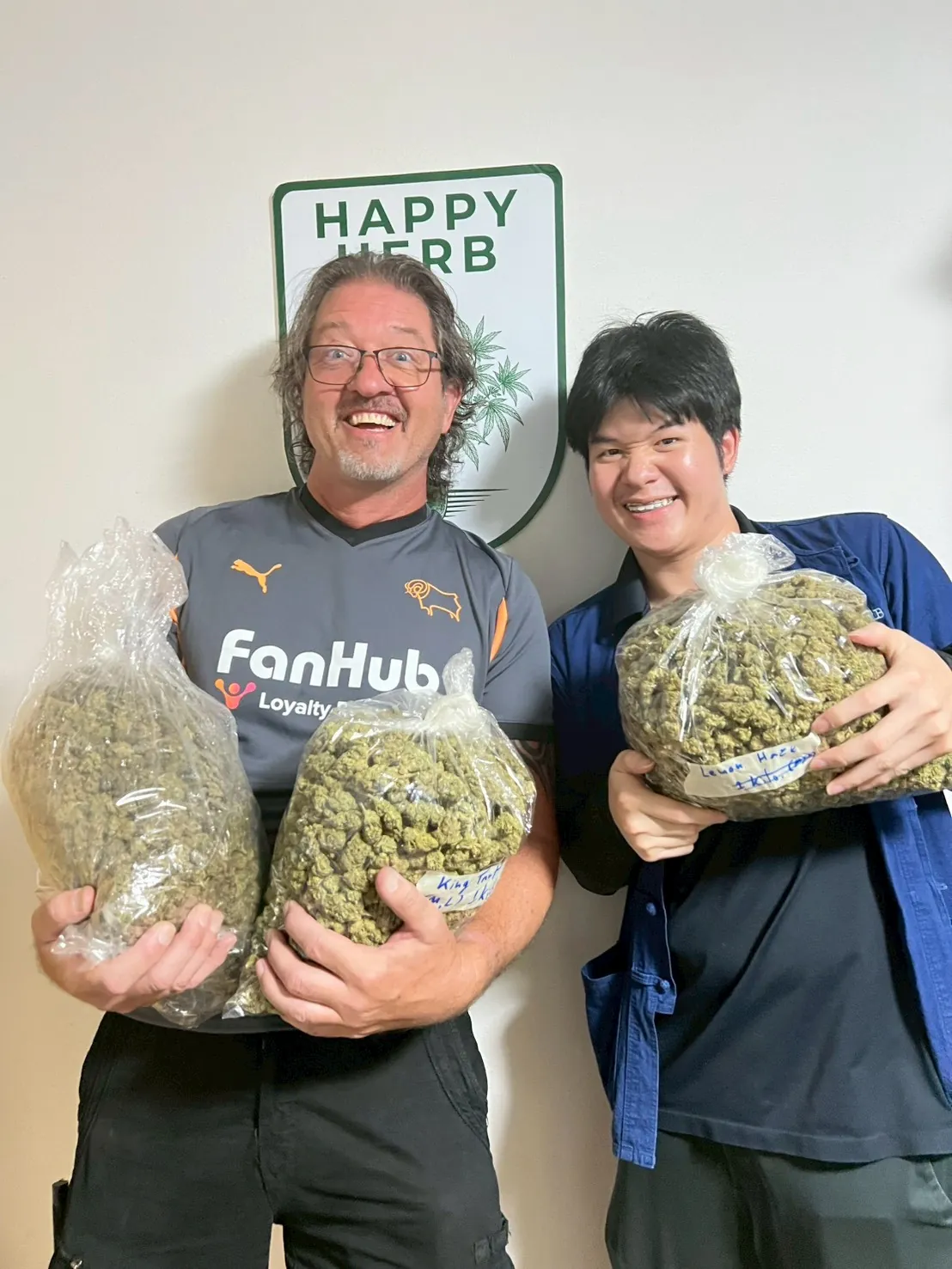 Two guests holding bags of harvested cannabis flowers